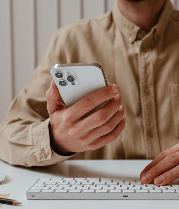 Persona sosteniendo un celular mientras digita un teclado